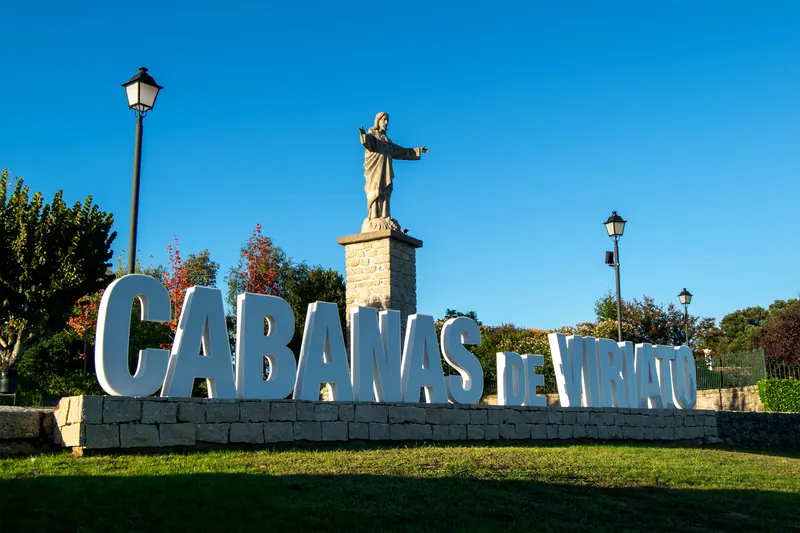 Letreiro com o nome Cabanas de Viriato e a estátua de Cristo-Rei ao fundo