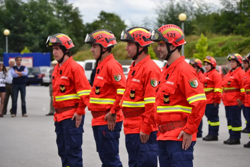 Bombeiros em formatura com capacetes e fardamento de proteção